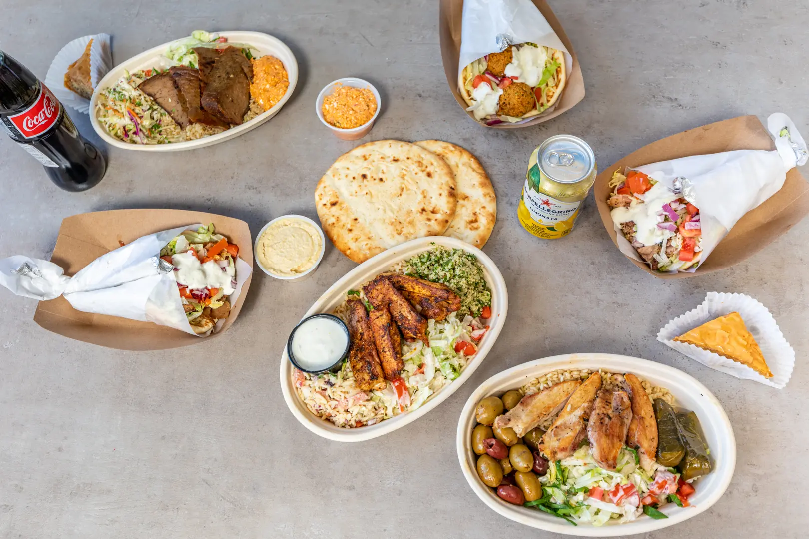A spread of Skull Creek Greek pitas, plates, fries, salads and sides