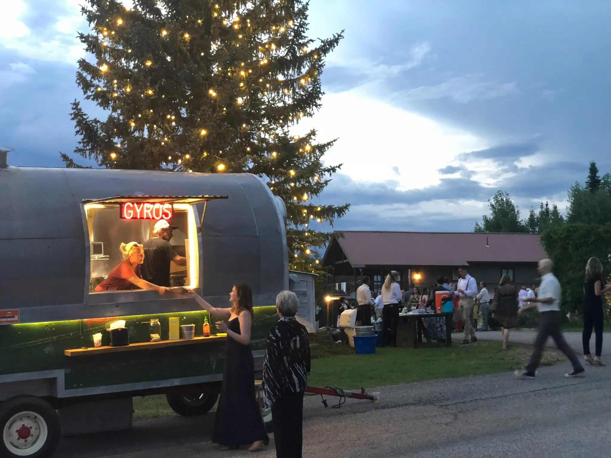 The illuminated Skull Creek Greek The Wagon serving guests at an evening event